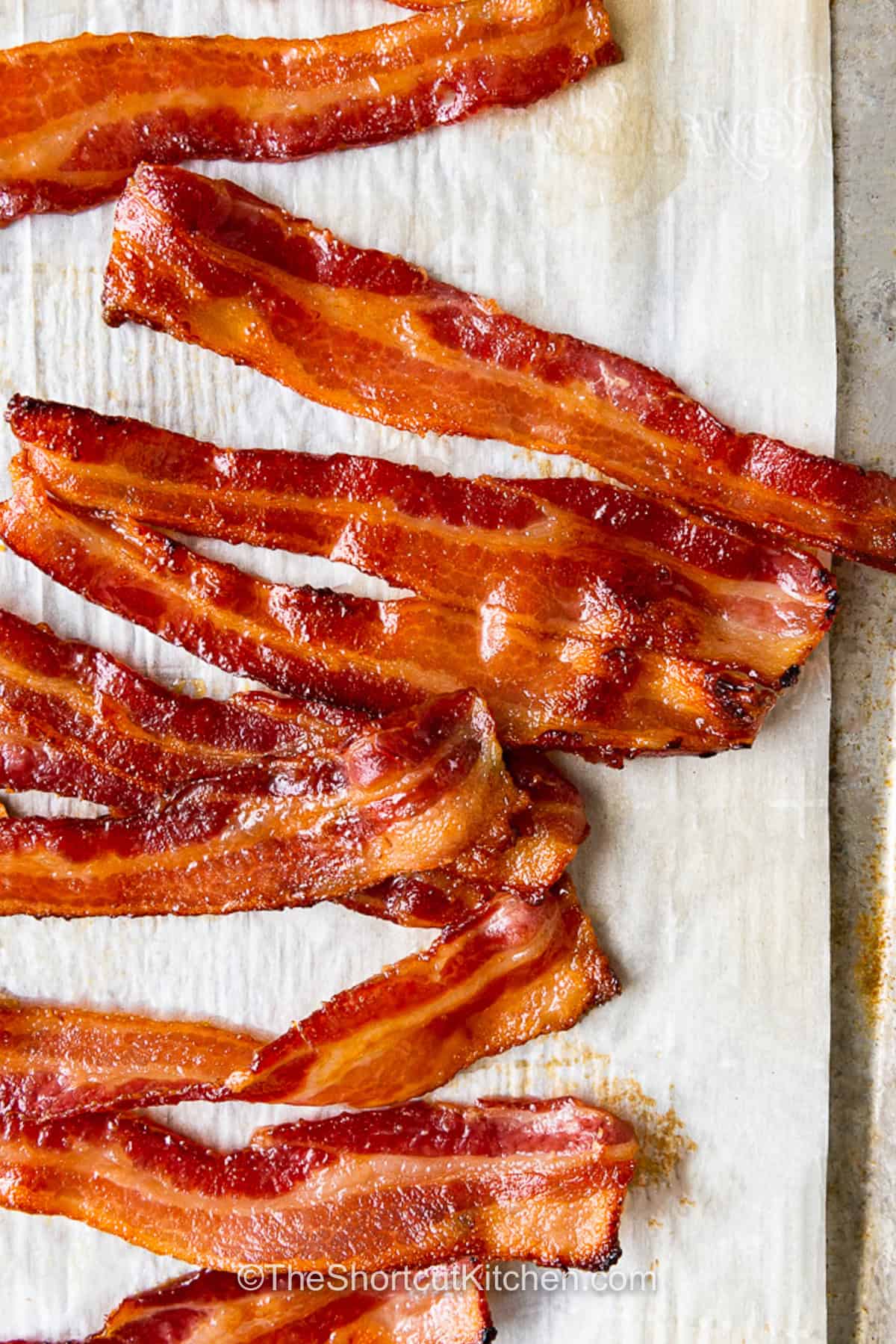 Weekend mornings are better with brown sugar bacon on the breakfast table. A sprinkle of brown sugar transforms ordinary bacon into a sweet and savory treat with crisp edges and a delicious caramelized coating. This easy candied bacon pairs well with eggs, pancakes, waffles, and French toast. It is also a tasty choice for brunch or holiday mornings when you want something everyone will enjoy. Save this simple recipe and make it for your next breakfast. #theshortcutkitchen brown sugar bacon draining on paper towels.