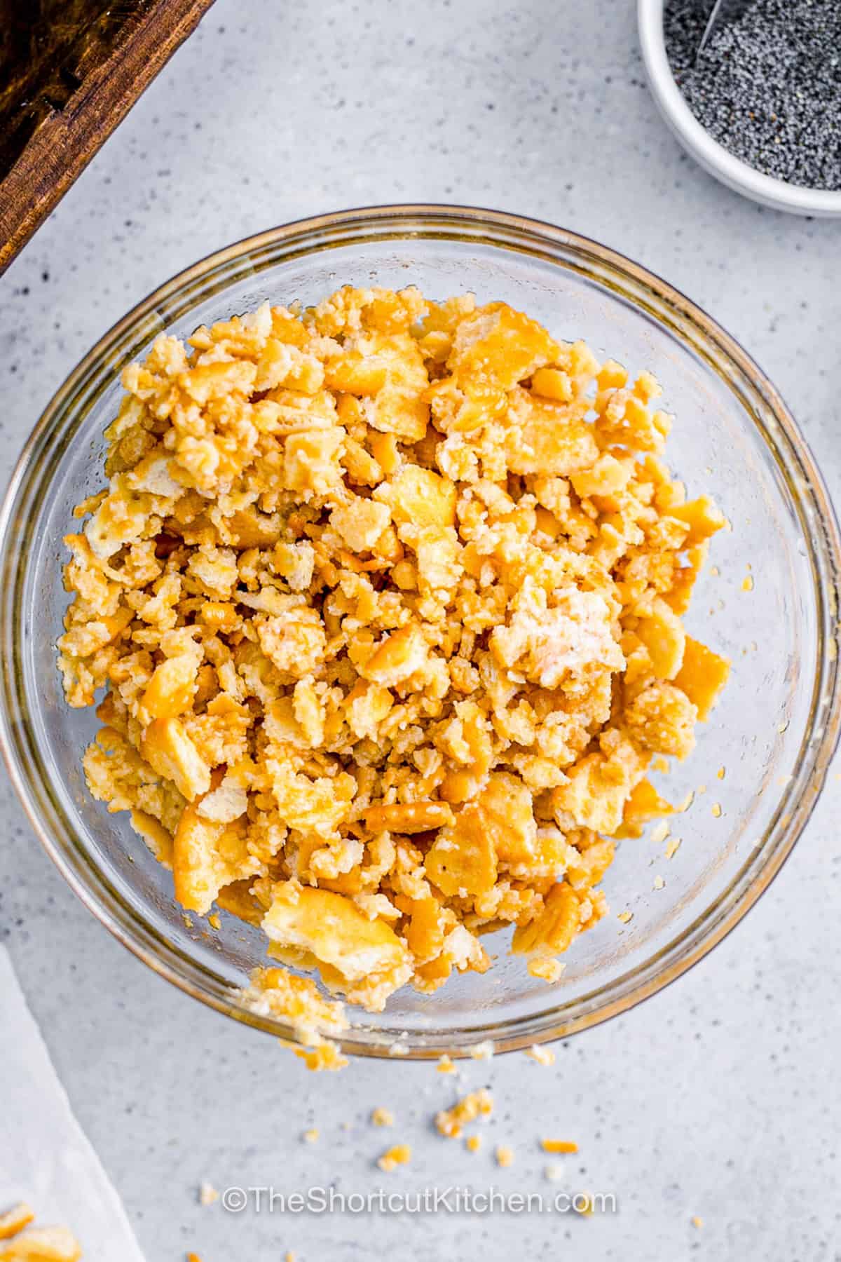 Chicken poppyseed casserole is creamy comfort food with a shortcut twist. Rotisserie chicken makes prep fast, while cream of chicken soup, Greek yogurt, cheddar, mozzarella, and poppy seeds create a rich and savory filling. Crushed Ritz crackers tossed with butter give this baked chicken casserole its irresistible golden crunch. It is ready in about 40 minutes and serves eight. Save this easy casserole recipe today. #theshortcutkitchen bowl of Chicken Poppyseed Casserole topping.