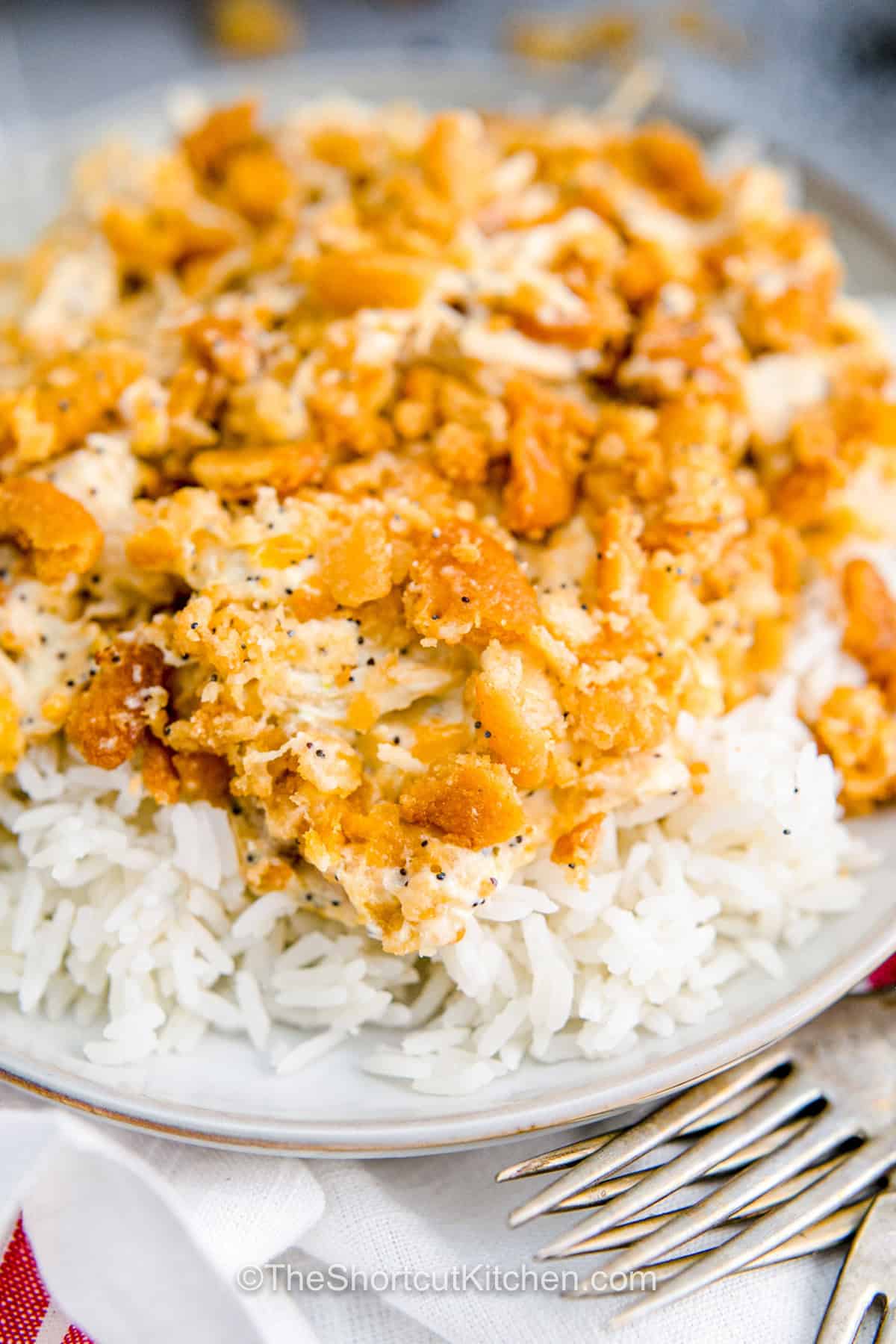 This creamy chicken poppyseed casserole has everything a cozy dinner needs, including tender chicken, melted cheese, a savory cream sauce, poppy seeds, and a golden Ritz cracker topping. The easy oven casserole takes just 5 minutes to assemble because the chicken is already cooked. Add optional bacon for smoky flavor or keep it classic. Save this chicken casserole with Ritz crackers for an easy family dinner. #theshortcutkitchen delicious Chicken Poppyseed Casserole on white rice.