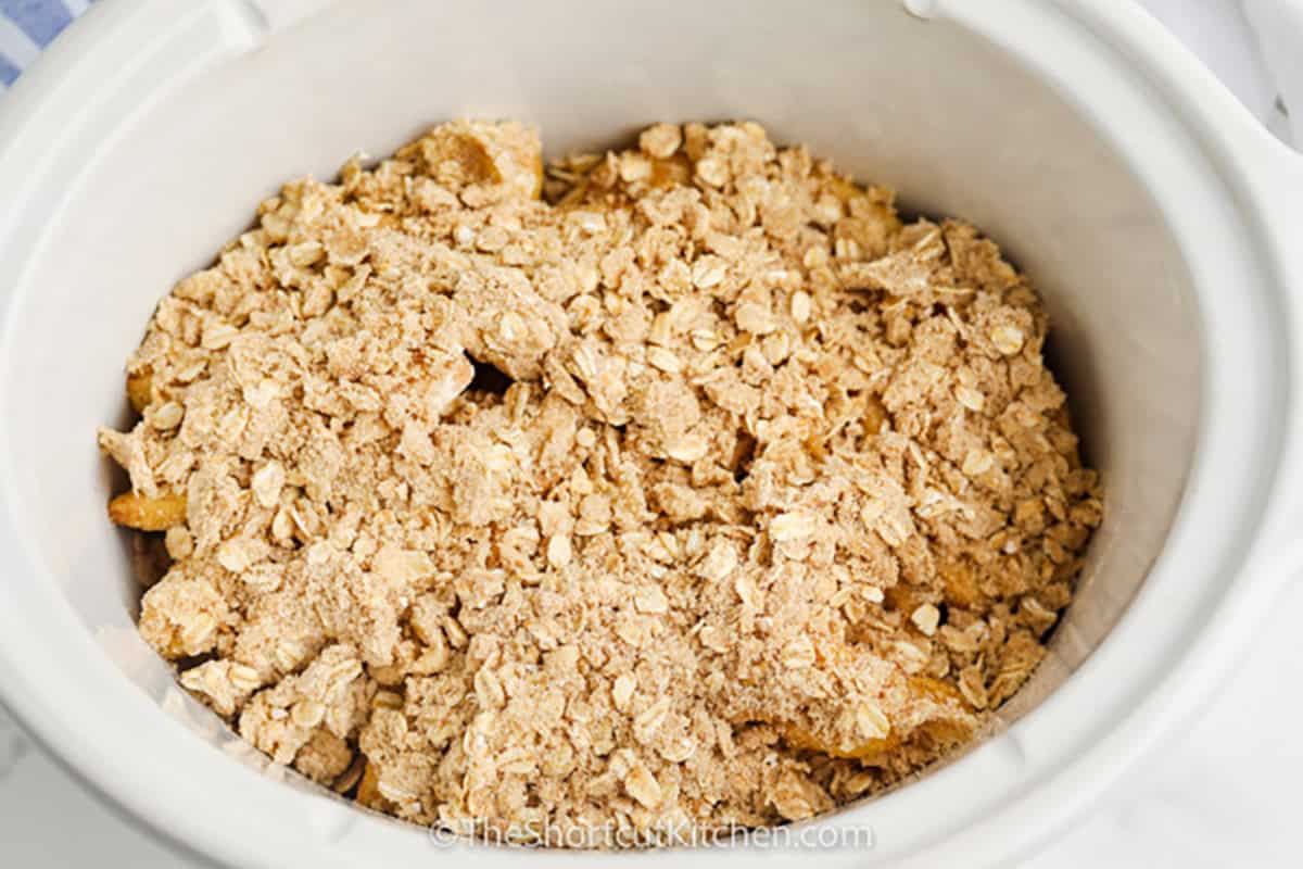 Make Slow Cooker apple crisp when the craving for warm cinnamon apples hits. Fresh apples are tossed with sugar and cinnamon, then covered with a buttery brown sugar and old-fashioned oat topping. The crockpot cooks everything until warm and tender while keeping the oven free. It is an easy fall dessert for family dinners, holidays, or entertaining. Save this crockpot apple crisp and try it soon. #theshortcutkitchen Crock Pot Apple Crisp before baking