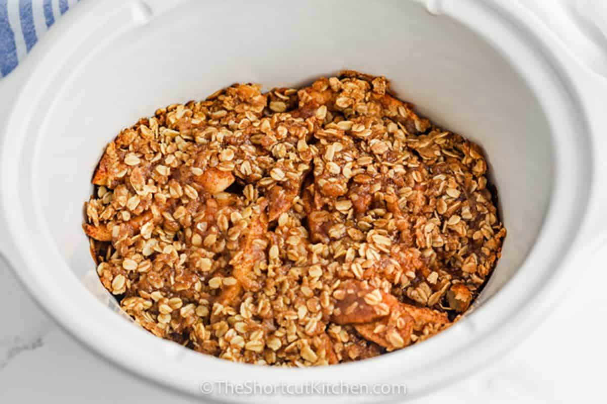 This Slow Cooker apple crisp turns fresh apples, cinnamon, brown sugar, butter, and rolled oats into a cozy homemade dessert with minimal prep. The crockpot gently cooks the apples until tender while the oat crumble becomes buttery and delicious. Serve this easy apple crisp warm with vanilla ice cream or caramel sauce for the ultimate fall treat. Pin this easy slow cooker dessert for apple season. #theshortcutkitchen Crock Pot Apple Crisp in the pot
