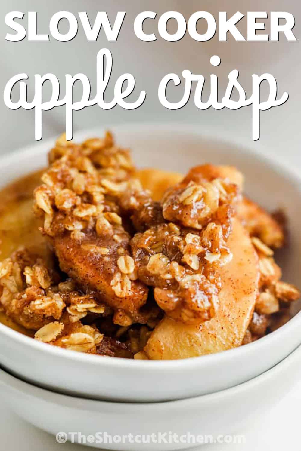 Make Slow Cooker apple crisp when the craving for warm cinnamon apples hits. Fresh apples are tossed with sugar and cinnamon, then covered with a buttery brown sugar and old-fashioned oat topping. The crockpot cooks everything until warm and tender while keeping the oven free. It is an easy fall dessert for family dinners, holidays, or entertaining. Save this crockpot apple crisp and try it soon. #theshortcutkitchen bowl of Crock Pot Apple Crisp with writing