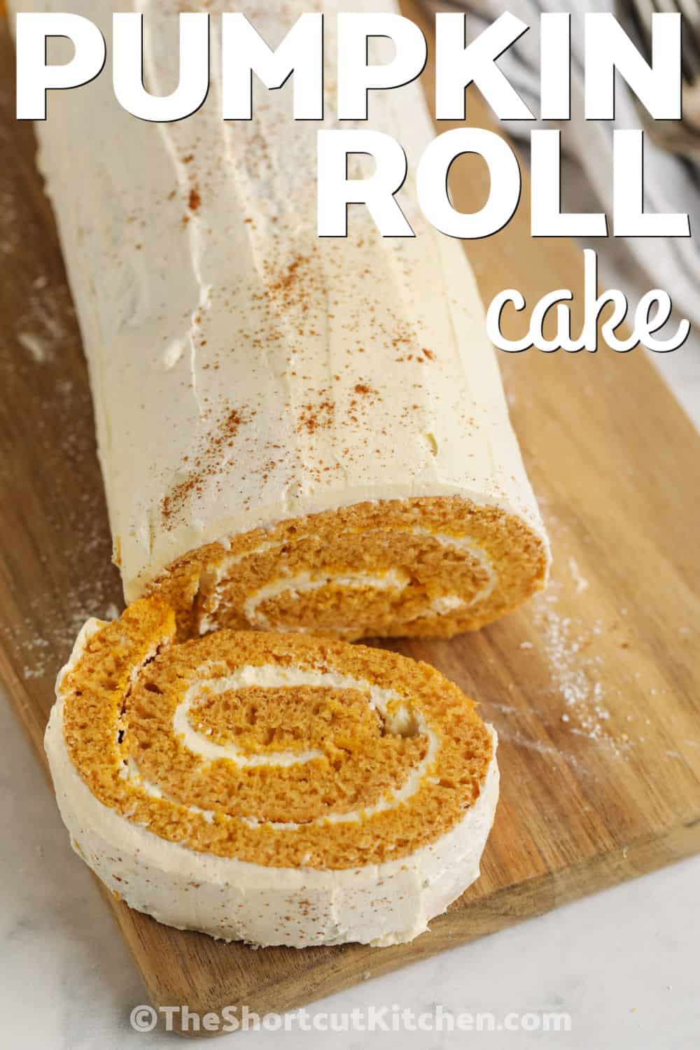 Cozy pumpkin spice flavor meets fluffy cream cheese filling in this easy pumpkin roll cake. Using yellow cake mix and canned pumpkin cuts down on measuring while still producing a soft cake that rolls beautifully. Serve this chilled pumpkin cake roll for Thanksgiving, potlucks, coffee breaks, or fall gatherings. It looks impressive without complicated baking. Pin this shortcut pumpkin dessert to try this season. #theshortcutkitchen Pumpkin Roll Cake with a slice cut out with a title.
