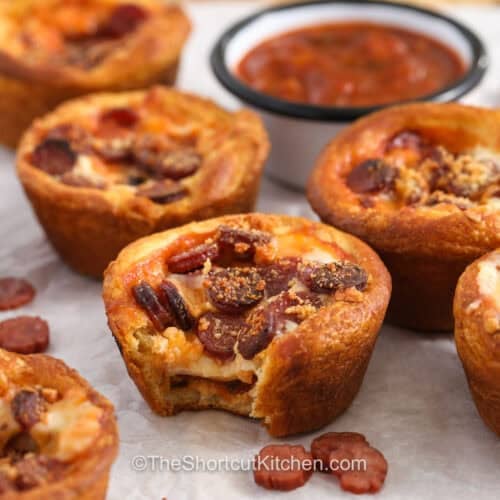 Pizza Cupcakes with marinara sauce in dish in background.
