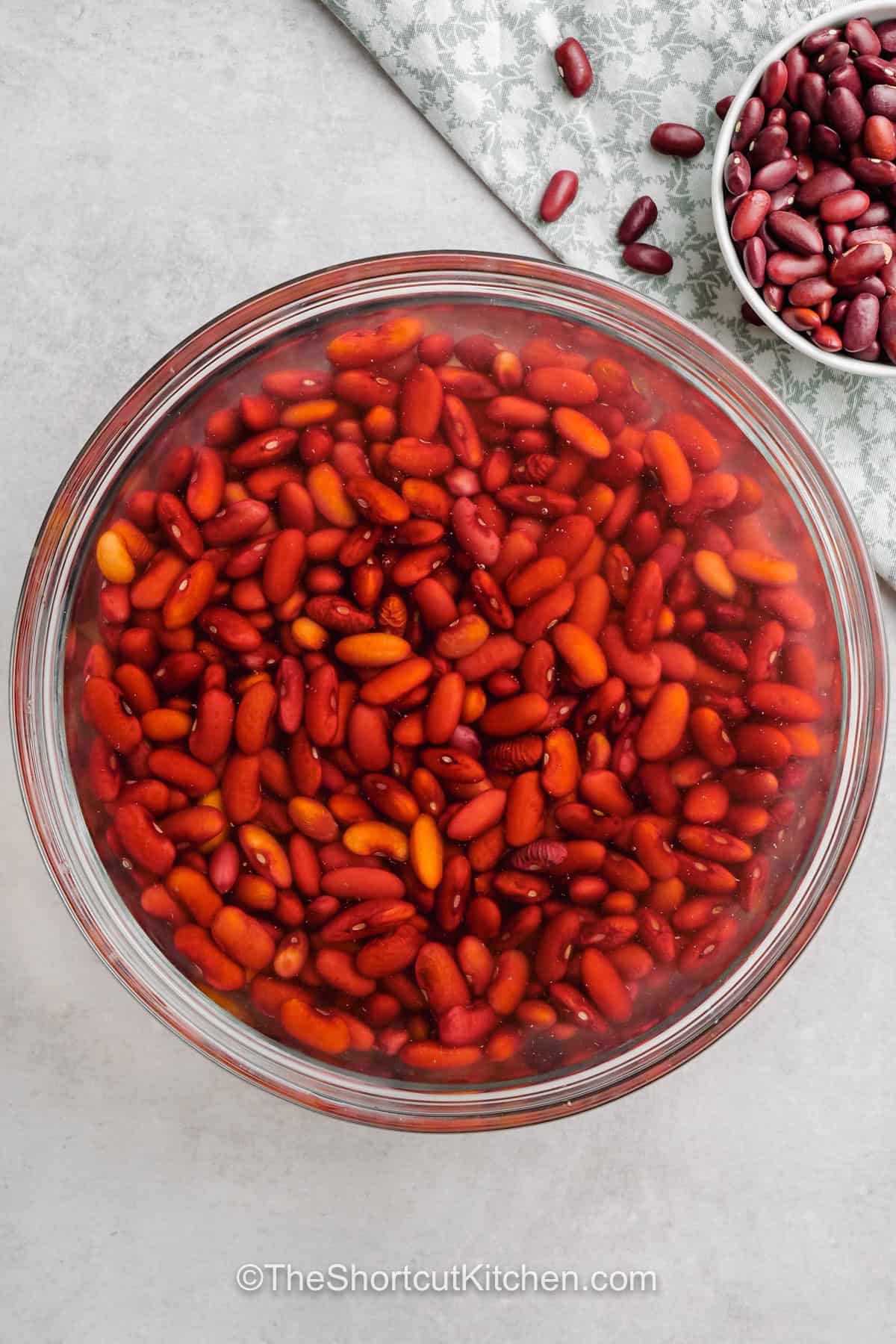 This easy red beans and rice recipe turns inexpensive kidney beans and rice into a hearty stovetop meal. Andouille sausage and bacon bring smoky flavor while peppers, celery, thyme, cayenne, and hot sauce add layers of savory heat. A gentle simmer makes the beans tender and creamy without complicated techniques. Save this red beans and rice with sausage recipe for comfort food night. #theshortcutkitchen soaking beans In water to make Easy Red Beans and Rice .