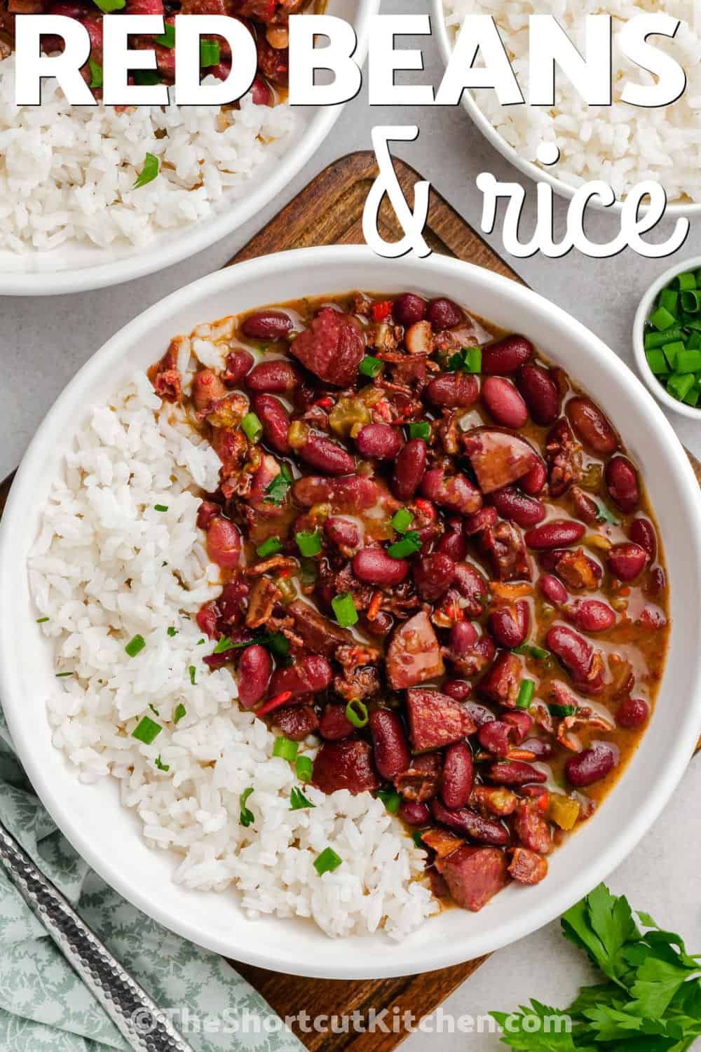 Easy red beans and rice with andouille sausage is big on smoky, savory flavor. Soaked kidney beans cook on the stovetop with bacon, sausage, onion, celery, bell peppers, chicken broth, thyme, cayenne, and hot sauce until deliciously tender. Spoon the creamy beans over white rice for a hearty dinner made from simple ingredients. Pin this cozy red beans and rice recipe for later. #theshortcutkitchen bowls of savory Easy Red Beans and Rice with writing.