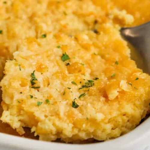 taking Corn Pudding Casserole out of the dish with a spoon.